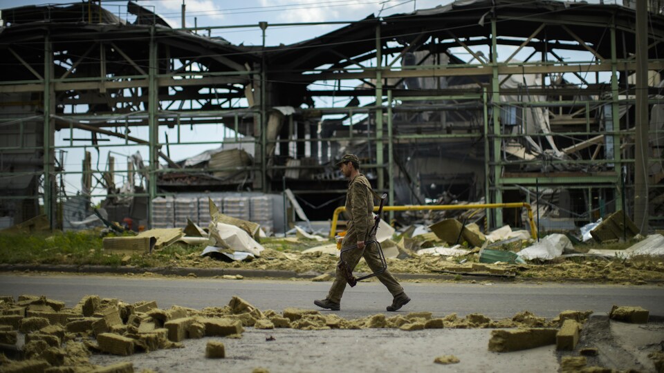 Un soldat ukrainien marche près d'une usine détruite.