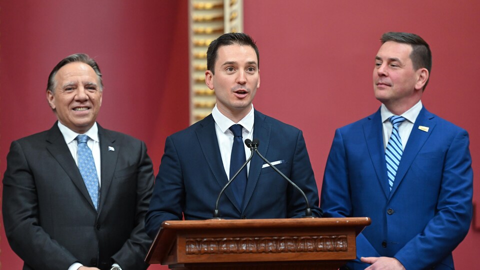 Le premier ministre François Legault et le secrétaire général de l'Assemblée nationale du Québec, Siegfried Peters, entourent le député de Borduas, Simon Jolin-Barrette, lors de l'assermentation.