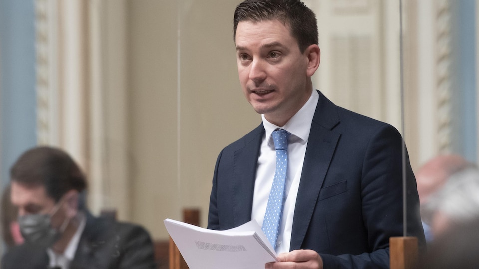 Simon Jolin-Barrette est debout à l'Assemblée nationale, tenant des feuilles dans ses mains.