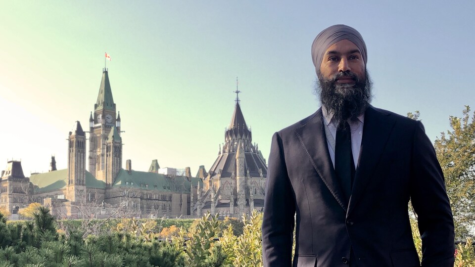 Jagmeet Singh debout avec le parlement d'Ottawa en arrière-plan.