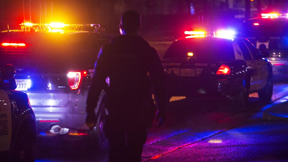 Un policier sort de son véhicule la nuit.