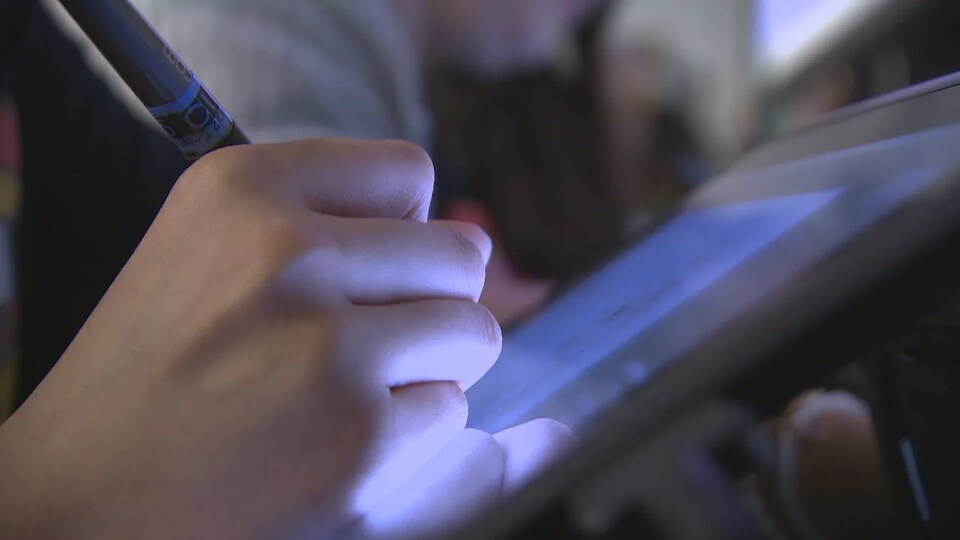 Une main utilise un stylet sur une tablette graphique.