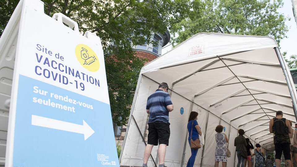 Des gens font la file sous une tente afin de recevoir leur vaccin contre la COVID-19.