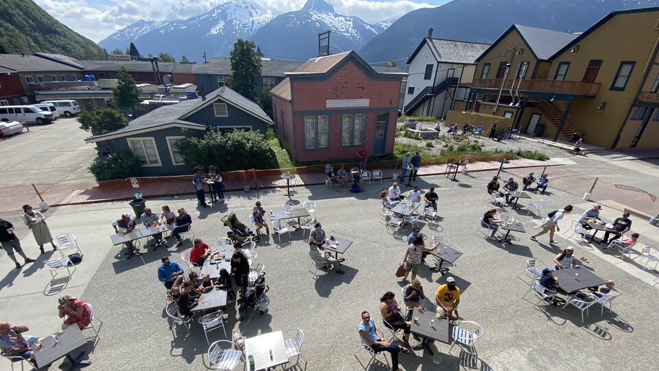 Des tables et des clients sont installés au milieu de la rue avec les montagnes en arrière-plan.