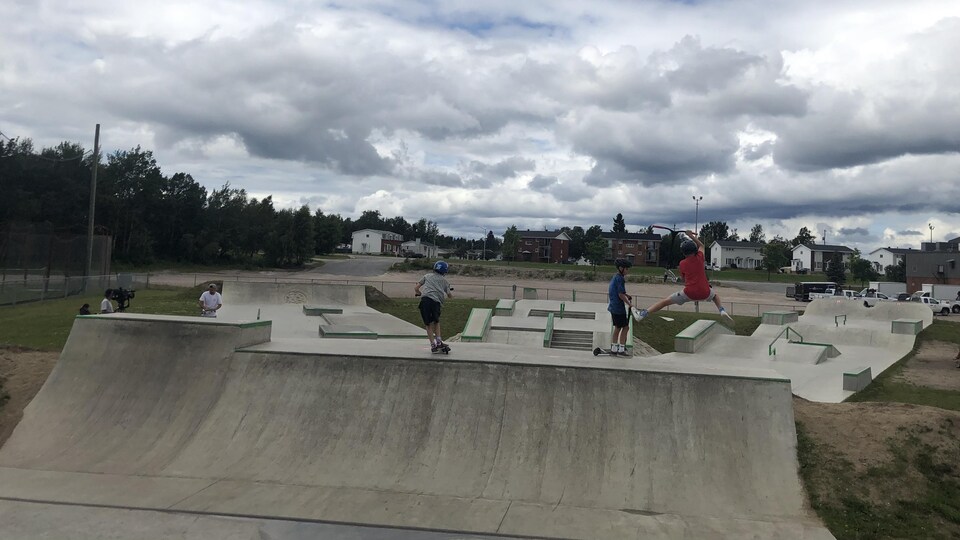 Quatre jeunes font du skate dans le parc ce skate lors d'une journée ennuagée.