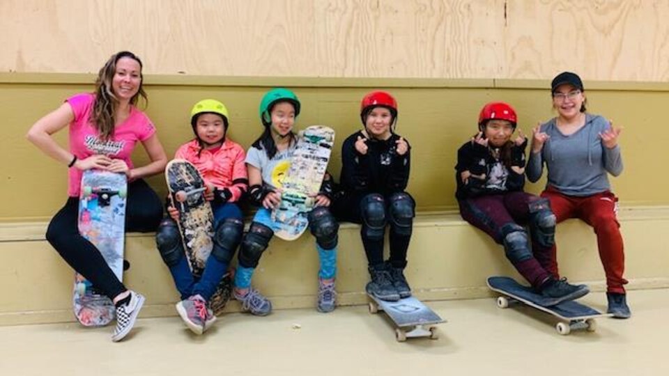 Des gens dans une salle avec des protections de planche à roulettes et des planches à roulettes.