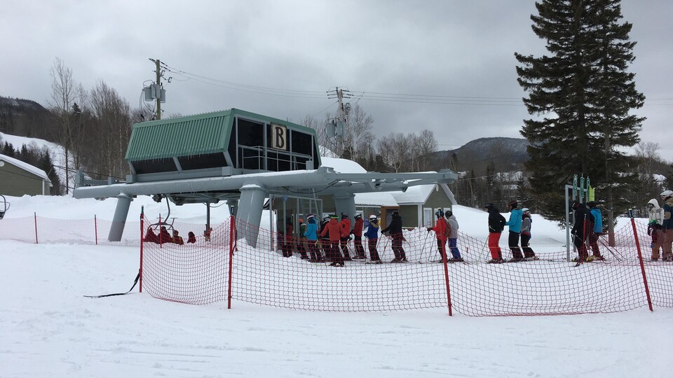 Des skieurs attendent à proximité d'une remontée mécanique du Mont Édouard.