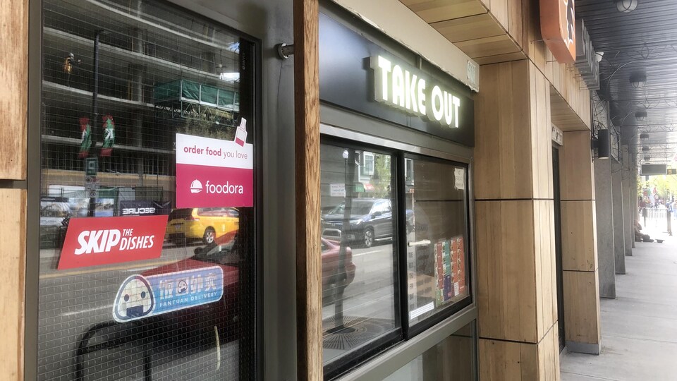 Devanture d'un restaurant. Sur la porte, il y a des autocollants d'entreprises de livraison comme Foodora et Skip The Dishes.