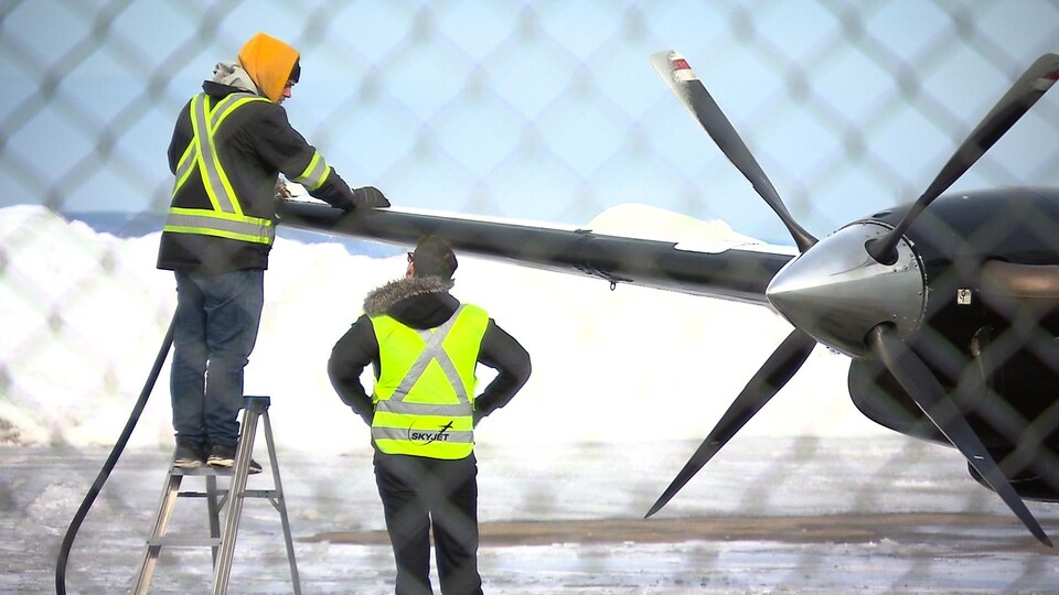 Des employés de Sky Jet près de l'aile d'un appareil.
