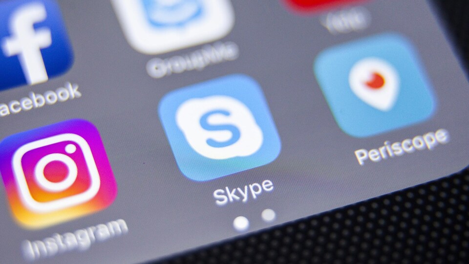 Un gros plan sur l'écran d'un téléphone qui affiche les icônes de différentes applications, dont Facebook, Instagram, Skype et Periscope.