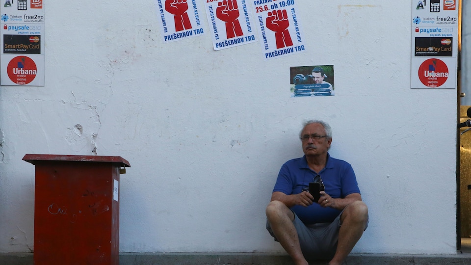 A man sits under anti -government posters in the Slovenian capital, Ljubljana.