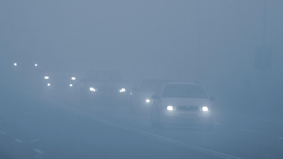 Des voitures conduisent dans le brouillard.