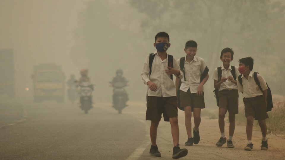 Des jeunes en Indonésie se rendent à pied à l'école malgré un smog épais. 