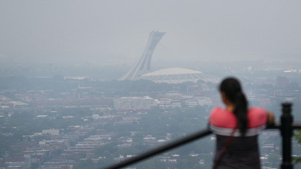 Une femme regarde le stade, accotée sur une rambarde.