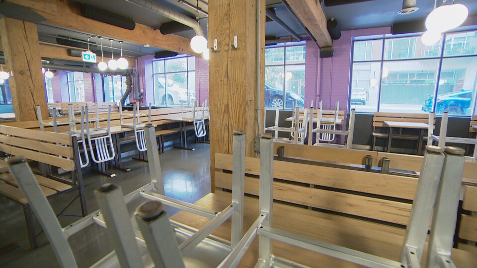 Une salle vide avec des chaises rangées par-dessus des tables.