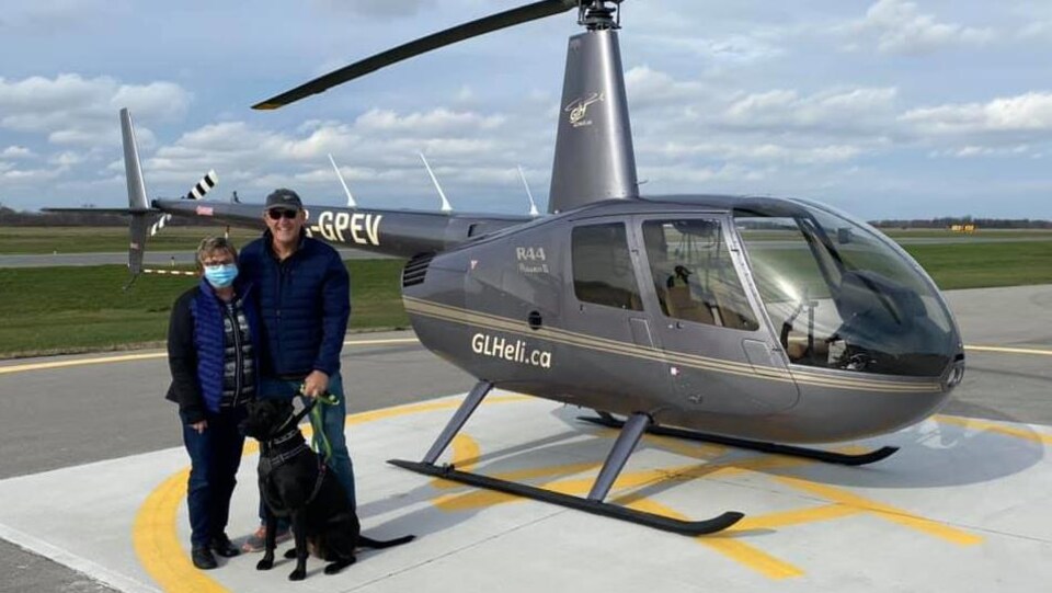 Un couple de vacanciers devant un hélicoptère.