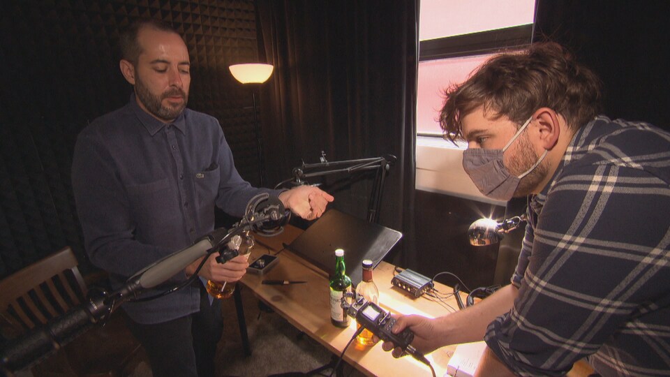 Deux hommes dans un studio d'enregistrement devant des micros. 