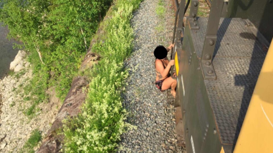 Une jeune femme en maillot de bain s'agrippe à un train en mouvement.