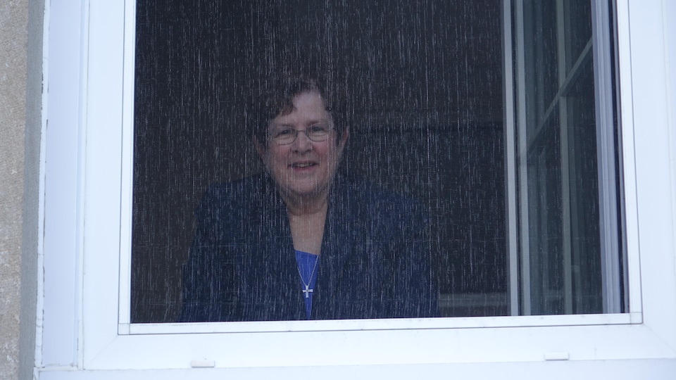 Sœur Gabrielle Côté, à la fenêtre, s'adresse au journaliste Denis Leduc qui se trouve à l'extérieur du bâtiment.