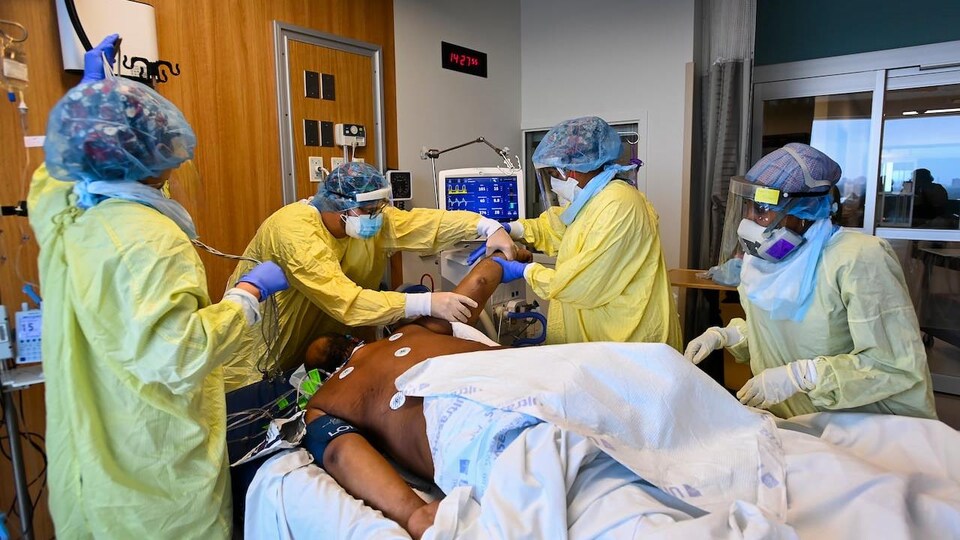 Un homme sur une civière entouré de quatre membres du personnel d'un hôpital.