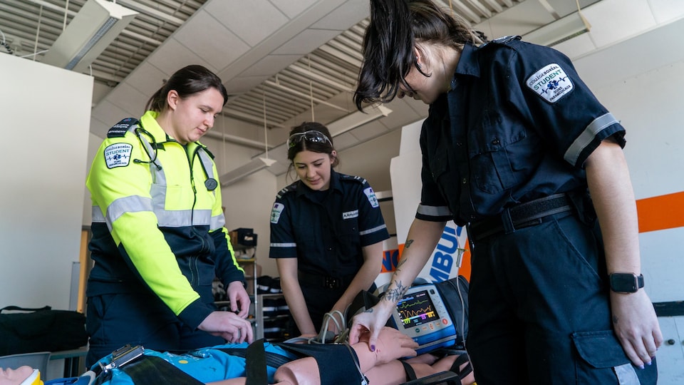 Trois étudiantes penchées sur un mannequin médical.