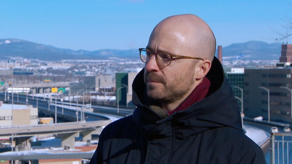 Sol Zanetti lors d’une entrevue accordée à l’extérieur l'hiver de jour. À l'arrière-plan, on aperçoit le quartier Limoilou.