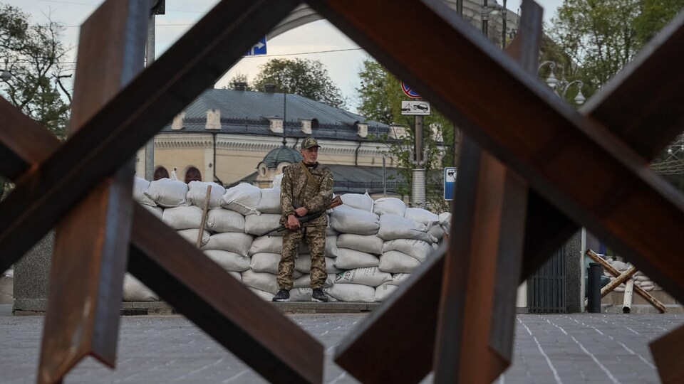 Un soldat debout derrière une barrière antichar.