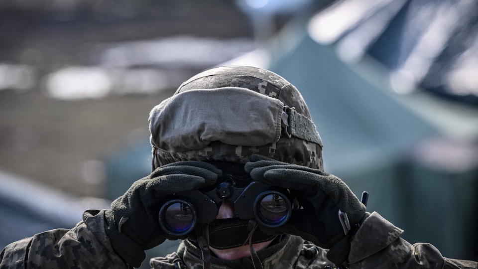 Un soldat ukrainien regarde dans des jumelles.