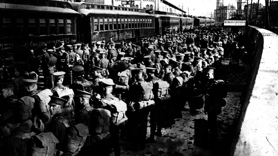 Des soldats attendent sur le quai d'une gare.