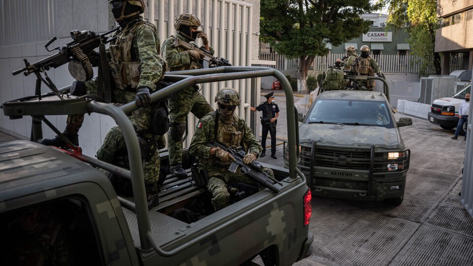 Des soldats s'entassent dans la boîte d'une camionnette.