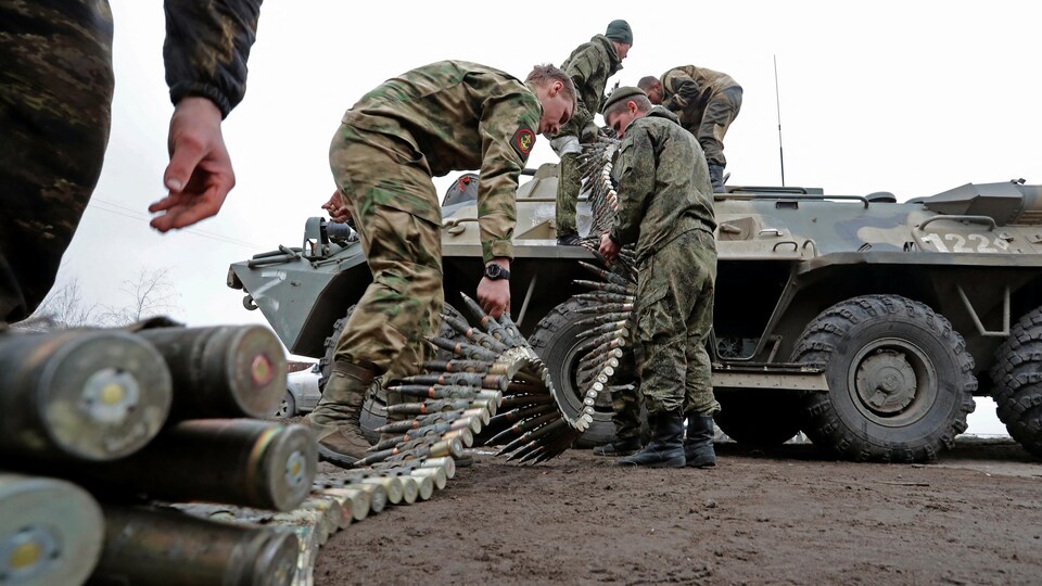 Des soldats chargent des munitions sur un blindé.