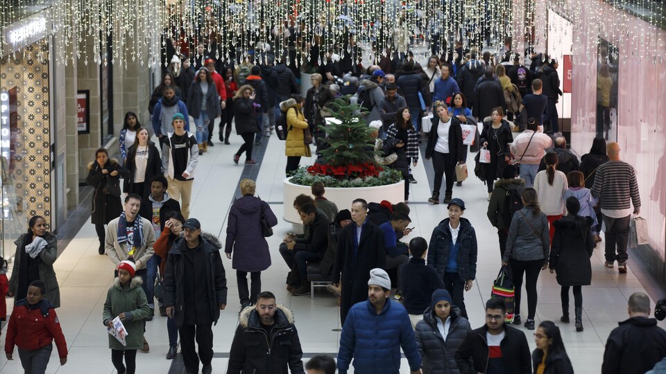 Une foule dans un centre commercial décoré pour Noël.