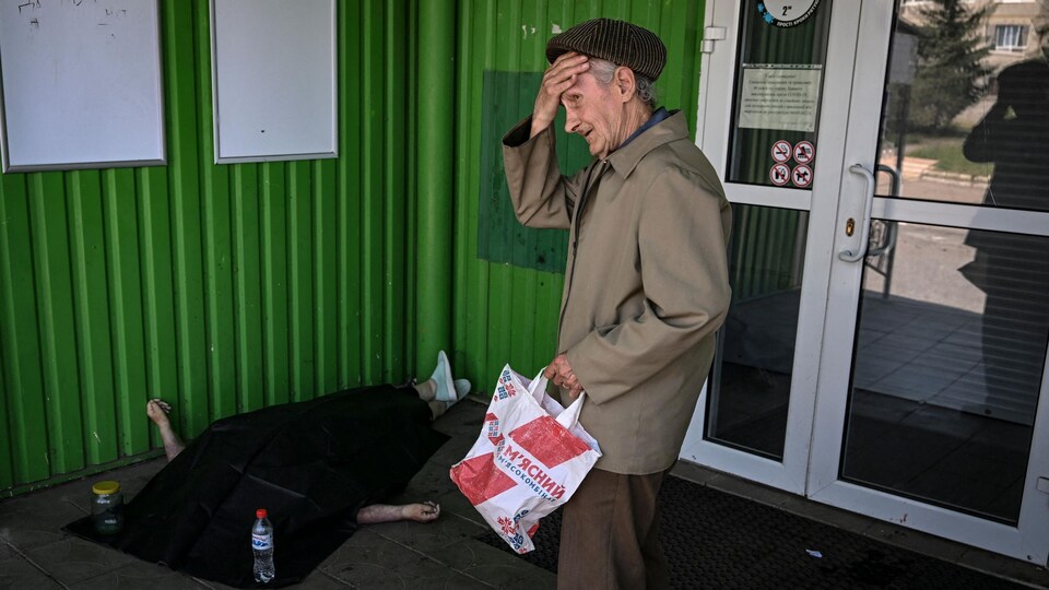 A man was standing near a corpse covered with a black blanket.