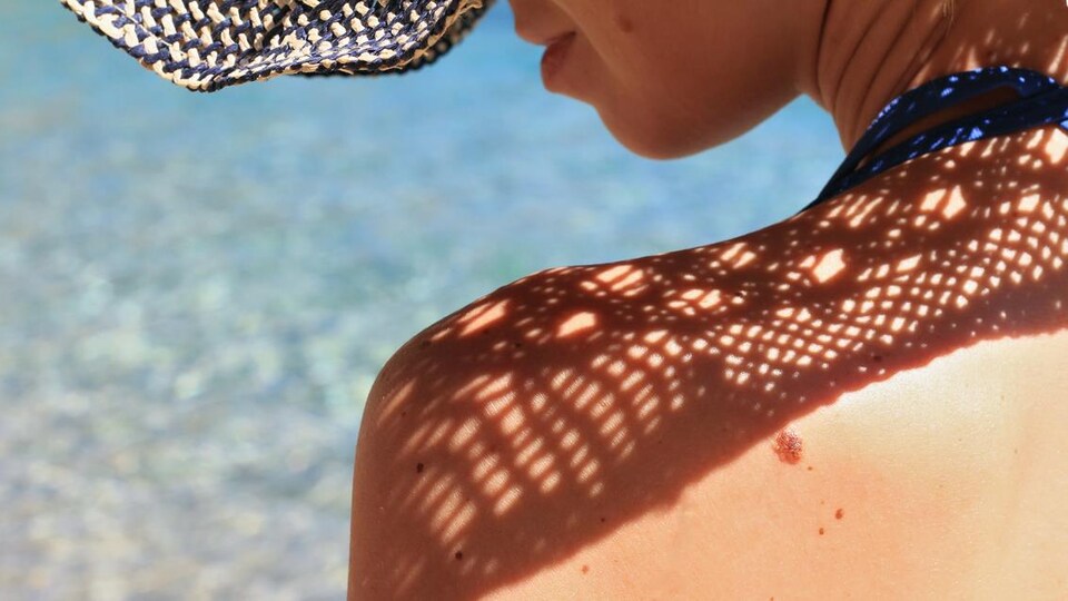 Une femme au bord de la mer porte un chapeau