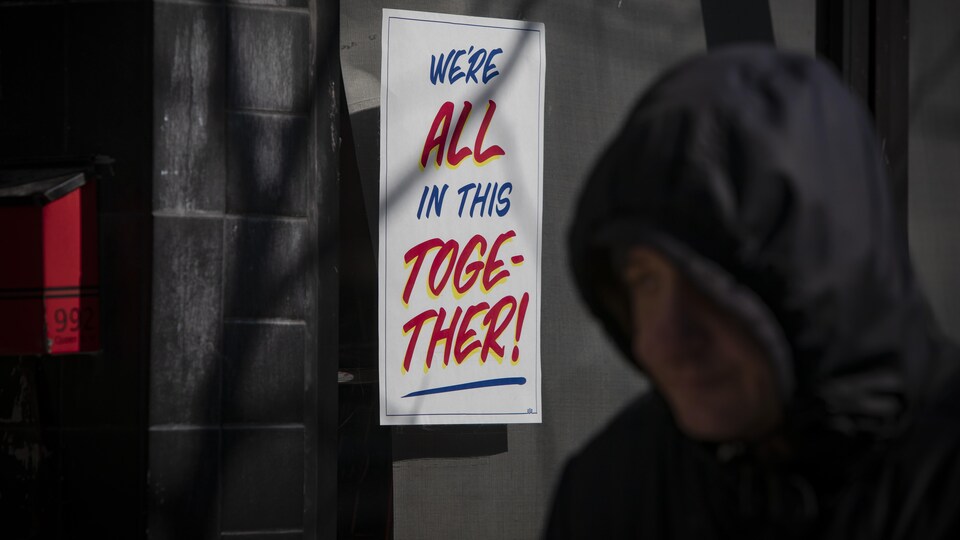 Une affiche de solidarité sur laquelle il est écrit en anglais « nous sommes tous ensemble dans cette situation » collée sur une vitrine d'un magasin torontois.