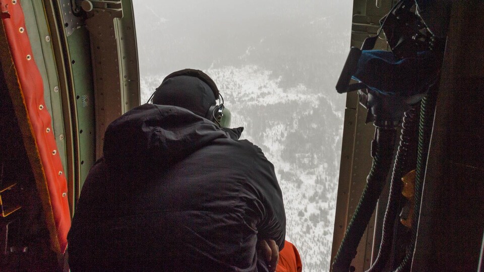 Un homme observe une forêt de haut, à bord d'un avion.