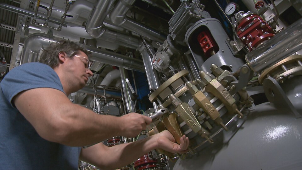 Un employé est en train de serrer une pièce dans une usine.