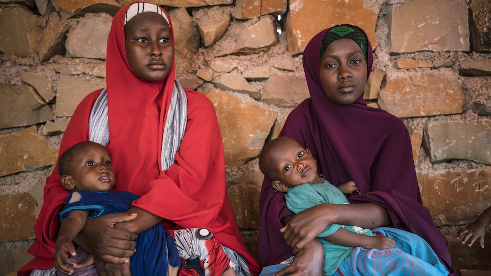 Deux mères somaliennes tiennent dans leurs bras leurs enfants souffrant de malnutrition