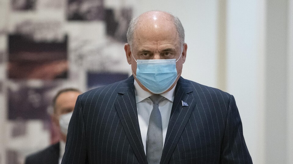 Pierre Fitzgibbon, portant un masque, regarde droit devant lui.
