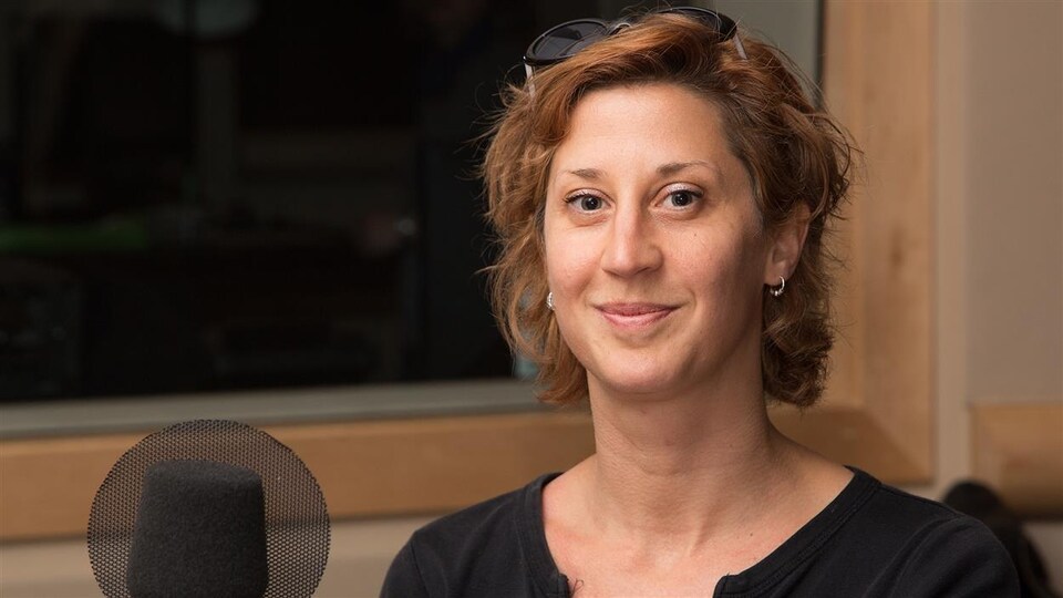 Sonia Cotten devant un micro assise dans un studio de radio.