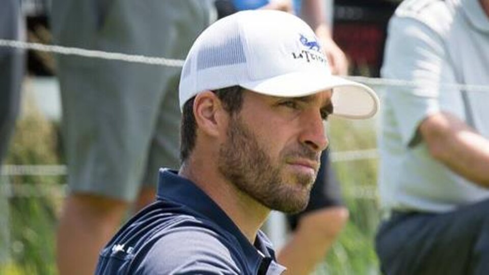 Sonny Michaud regarde au loin, appuyé sur son bâton de golf.