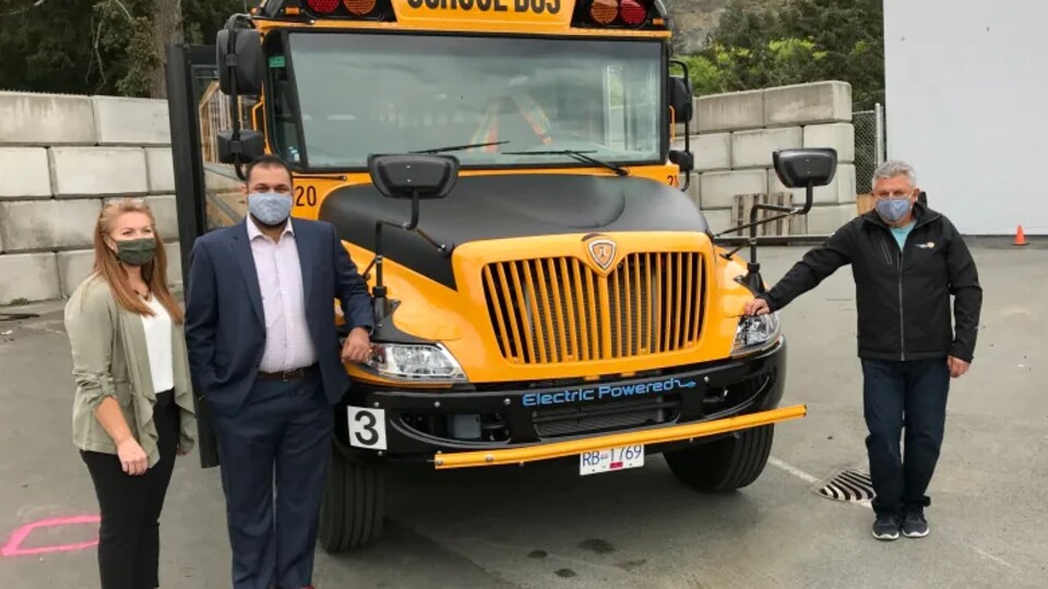 Trois personnes autour d'un autobus scolaire.