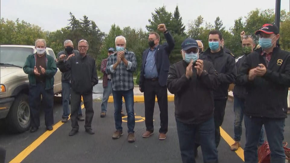 Plusieurs personnes portant le masque applaudissent ou brandissent le point.