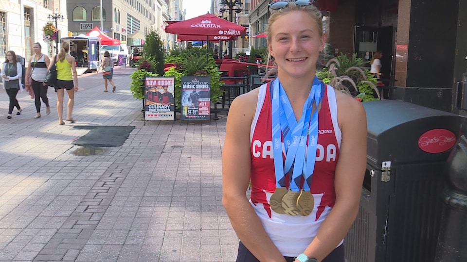 Sophia Jensen dans une rue piétonne d'Ottawa vêtue d'un maillot Canada, trois médailles d'or au cou.