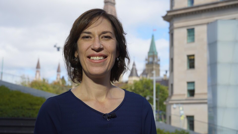 Sophie Chatel pose avec au loin le parlement d'Ottawa.