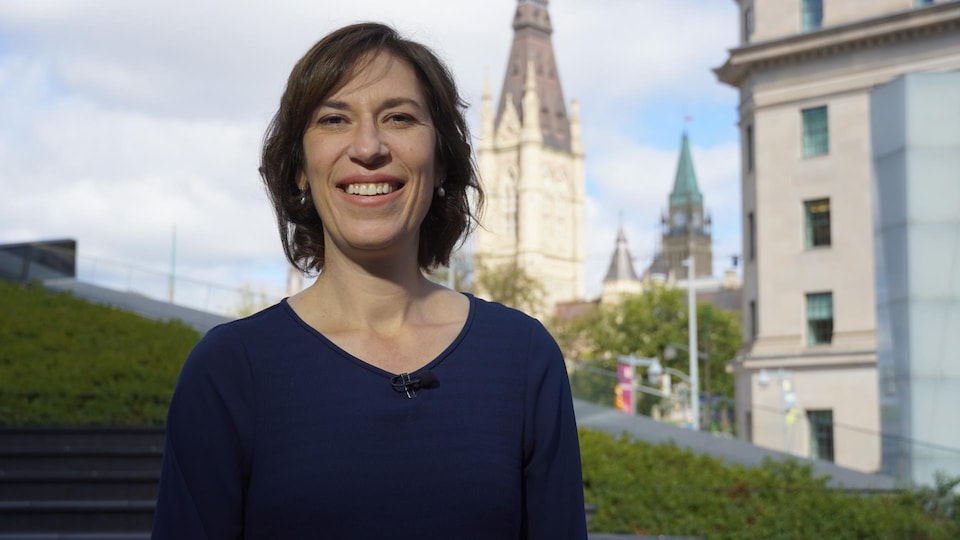 Sophie Chatel pose avec au loin le parlement, à Ottawa.