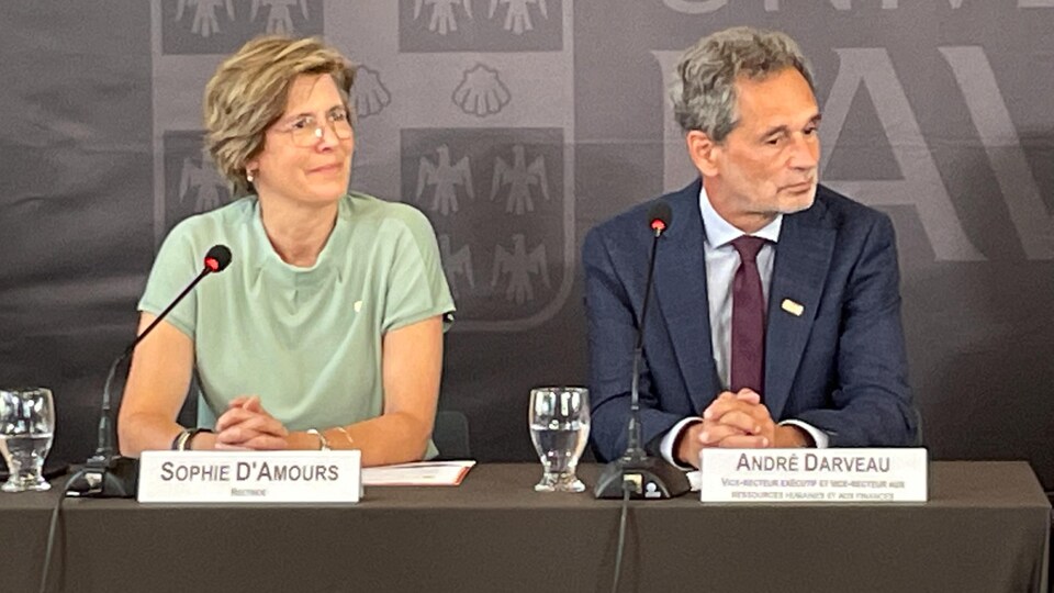 Sophie D'Amours écoute la question d'un journaliste lors d'une conférence de presse. Elle est assise à côté du vice-recteur André Darveau.
