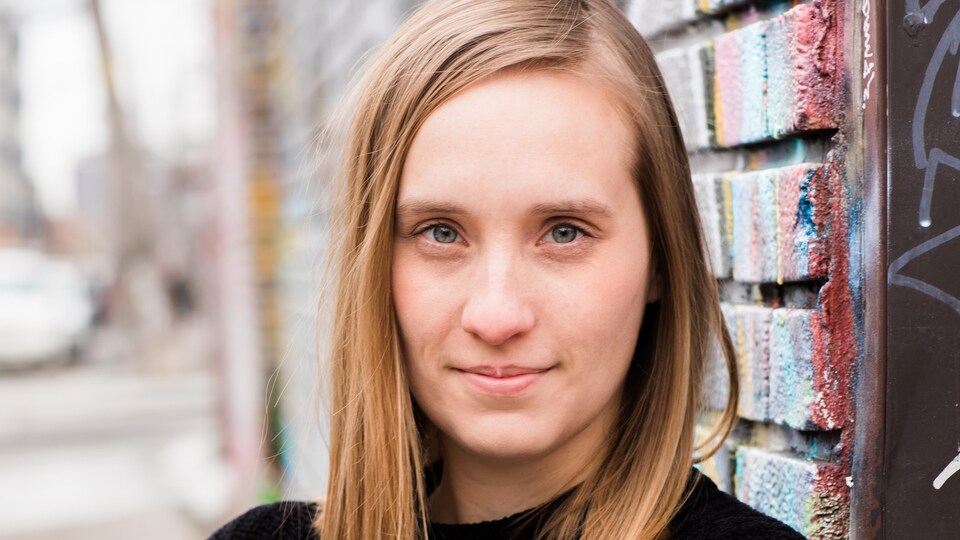 La cinéaste Sophie Dupuis, adossée à un mur de briques.