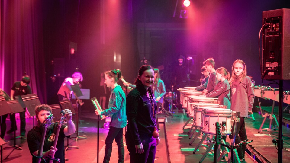 Sophie Jalbert sur une scène, entourée d'élèves et d'instruments de musique.