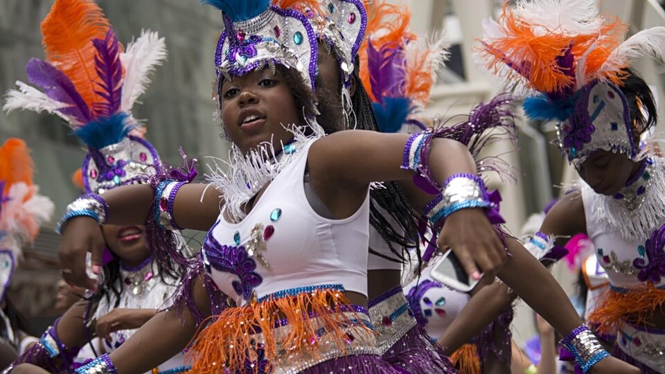 Une femme portes des costumes en plumes et des brillants pour le festival des caraïbes